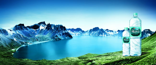 A image of Baeksansu bottled water against the backdrop of Cheonji Lake, located in the crater at the top of Mount Baekdusan.   Nongshim