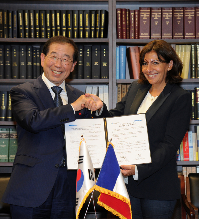 Seoul Mayor Park Won-soon shakes hands with his Paris counterpart Anne Hidalgo in New York on Tuesday.   Seoul Metroplitan Government