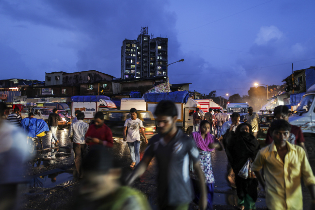 Pedestrians cross a road in the Dharavi slum area of Mumbai, India.    Bloomberg