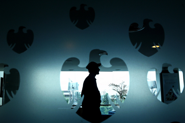 A silhouetted security guard is seen through the Barclays logo inside a bank branch in Karachi, Pakistan.   Bloomberg