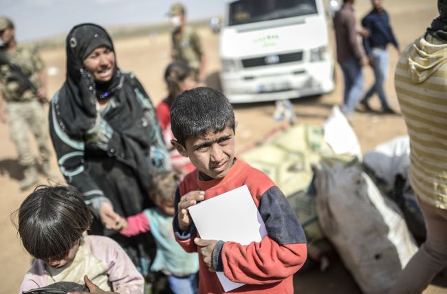Syrian Kurds, fleeing an onslaught by the jihadist Islamic State group, cross the border between Syria and Turkey at the southeastern town of Suruc in Sanliurfa province, Turkey, Saturday.   AFP-Yonhap
