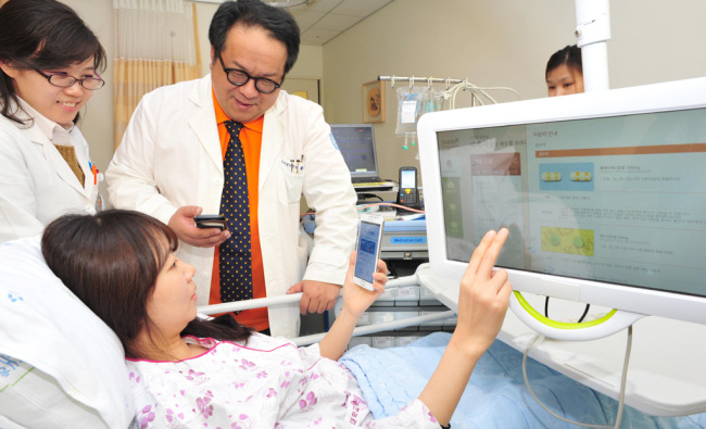A patient uses a personal electronic device to learn about her condition and required treatment with medical staff at Seoul National University Bundang Hospital.   Seoul National University Bundang Hospital