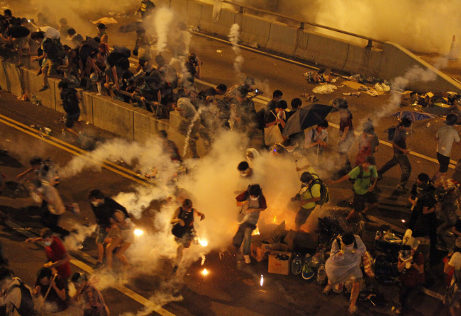 Riot police use tear gas against protesters after thousands of people blocked a main road at the financial Central district in Hong Kong on Sunday.   AP-Yonhap