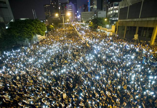 Protesters and student demonstrators hold up their cellphones in a display of solidarity during a protest outside the headquarters of the Legislative Council in Hong Kong on Monday.   AFP-Yonhap