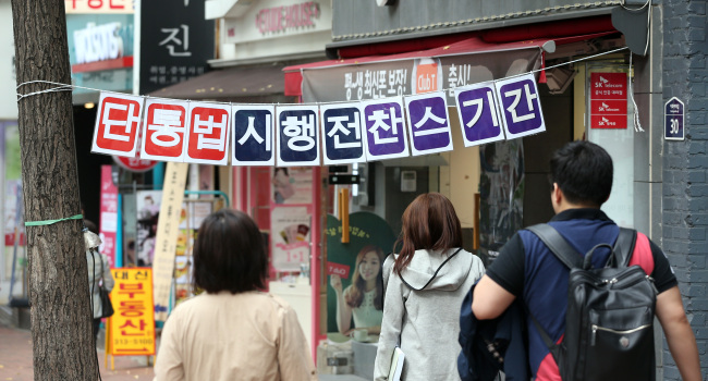 Seoul citizens pass telecom retailers advertising mobile phones and services in line with a revised law banning discriminatory subsidy plans.   Yonhap