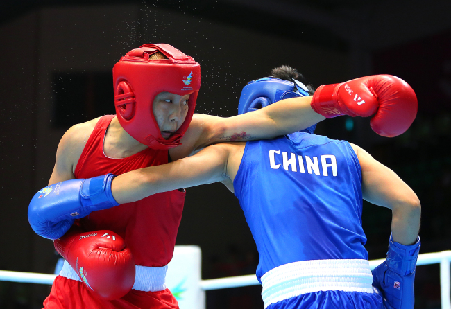 <YONHAP PHOTO-1369> <아시안게임> 펀치 날리는 박진아 (인천=연합뉴스) 황광모 기자 = 1일 인천 선학 복싱경기장에서 열린 2014 인천 아시안게임 여자 복싱 여자라이트급 결승 경기에서 한국의 박진아가 중국의 인 준후아와 펀치를 주고받고 있다. 박진아는 결국 판정패 해 은메달에 머물렀다. 2014.10.1 hkmpooh@yna.co.kr/2014-10-01 16:46:40/ <저작권자 ⓒ 1980-2014 ㈜연합뉴스. 무단 전재 재배포 금지.>
South Korean boxer Park Jin-a (left) won the silver medal in the women’s lightweight class at the Incheon Asian Games on Wednesday, earning the host country its first Asiad medal in the event. In the final held at Seonhak Gymnasium, Park lost to China’s Yin Junhua in a 0-2 decision.   Yonhap