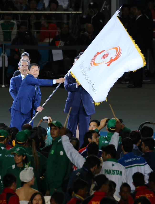 Incheon Mayor Yoo Jeong-bok waves a flag at the closing ceremony of the 17th Asian Games at the Asiad Main Stadium in Incheon on Saturday.   Yonhap
