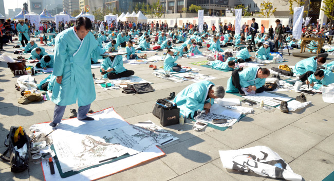 People participate in a Hangeul calligraphy contest on Hangeul Day, which marks the 1443 promulgation of the Korean alphabet, at Gwanghwamun Plaza in central Seoul on Thursday.   Kim Myung-sub/The Korea Herald