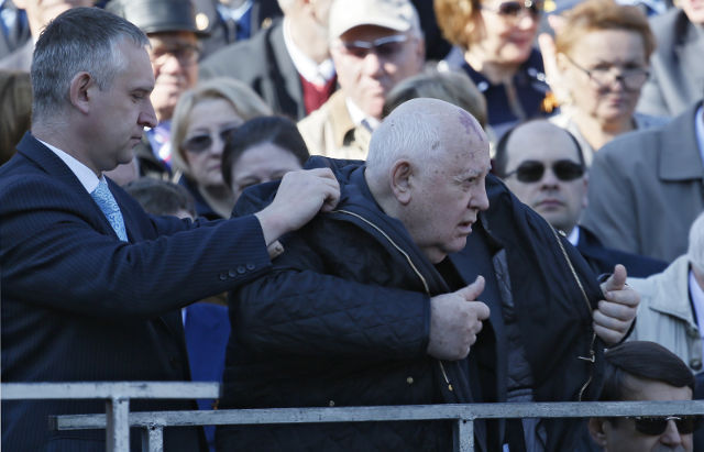 A man helps former Soviet leader Mikhail Gorbachev (right) to put on a coat prior to a military parade marking the 69th anniversary of the victory over Nazi Germany in World War II in Red Square in Moscow on May 9.   EPA