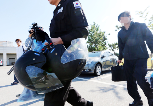 The Coast Guard officers head to the local police station for investigation on Friday, following the death of the captain of a Chinese fishing boat. (Yonhap)