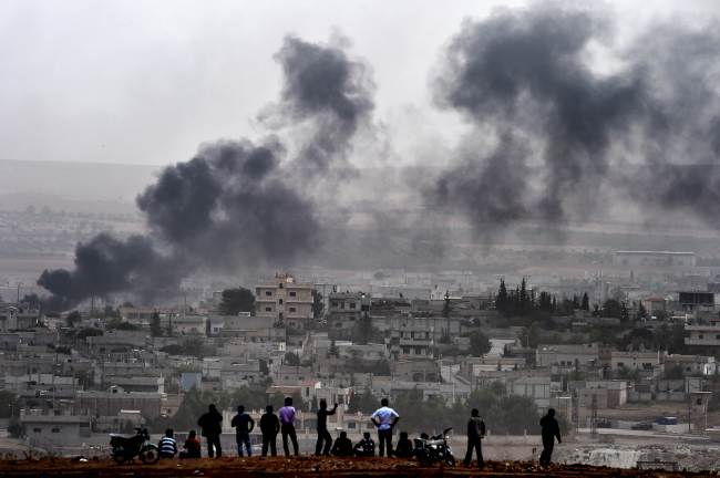 Kurdish people look at smoke rising in the Syrian town of Kobane, from the Turkish-Syrian border in Mursitpinar, Sanliurfa province, Turkey, Saturday.   AFP-Yonhap