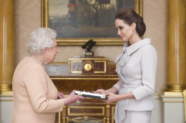 U.S. actress Angelina Jolie (right) is presented with the Insignia of an Honorary Dame Grand Cross of the Most Distinguished Order of St. Michael and St. George by Britain’s Queen Elizabeth II in the 1844 Room at Buckingham Palace in London on Friday.    AFP-Yonhap
