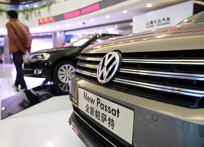 A visitor walks past Volkswagen Passat sedans displayed inside the Oriental Pearl Tower in the Pudong area of Shanghai.   Bloomberg