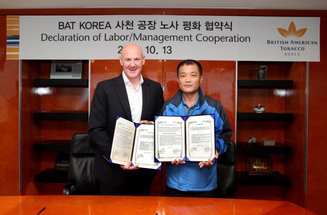 BAT Korea’s CEO Guy Meldrum (left) poses with its labor union leader Goo Seong-il at its head office in Seoul.   BAT Korea