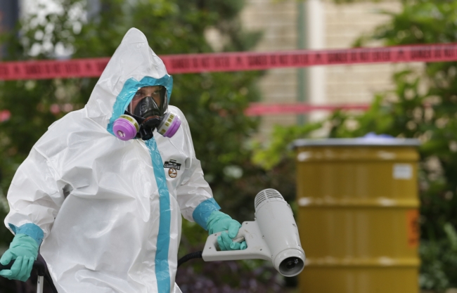 A worker in protective clothing cleans outside the apartment building of a hospital worker in Dallas on Sunday.   AP-Yonhap