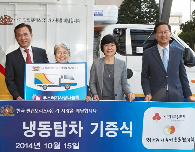 Philip Morris Korea’s corporate affairs director Kim Byung-chul (left), Leftovers’ Love Sharing Community board president Kang Myung-soon (second from left) and other community workers on Wednesday pose during a ceremony celebrating the tobacco firm’s freezer truck donation in Seoul.   Philip Morris Korea