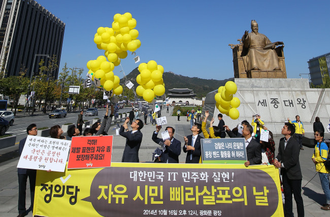 <YONHAP PHOTO-0634> IT민주화를 기원하며 (서울=연합뉴스) 김도훈 기자 = 16일 서울 광화문광장 세종대왕 동상 앞에서 정의당 천호선 대표를 비롯한 당직자들이 IT민주화를 염원하며 전단지 살포 퍼포먼스를 하고 있다. 정의당은 "정부가 국민의 안전을 심각하게 위협하는 행동을 하고 있는 전단지 살포는 묵인하고 사이버상에서의 자유로운 표현에 대해서는 필요 이상의 법 집행을 하고 있다"며 사이버 공간에서의 표현의 자유와 개인 사생활의 비밀과 자유 보장을 촉구했다. 2014.10.16 superdoo82@yna.co.kr/2014-10-16 13:28:15/ <저작권자 ⓒ 1980-2014 ㈜연합뉴스. 무단 전재 재배포 금지.>
Staff members of the progressive Justice Party distribute leaflets demanding freedom of expression with yellow balloons in their protest against the Justice Ministry and prosecution’s move to monitor the online activity of mobile users in Gwanghwamun, downtown Seoul, Thursday.   Yonhap