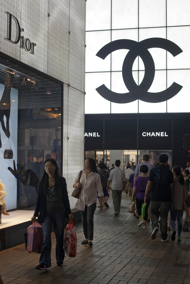 Shoppers walk past Christian Dior and Chanel stores in Hong Kong.   Bloomberg