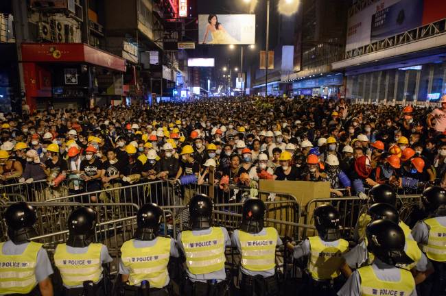 Riot police (left) clash with pro-democracy protesters at the Mongkok shopping district, Hong Kong, Sunday. (AFP)