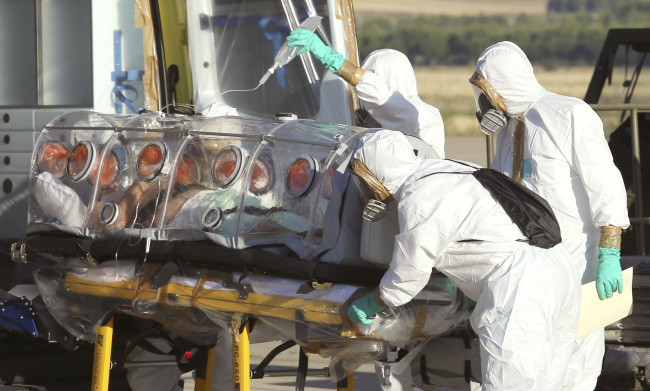 Aid workers and doctors transfer Miguel Pajares, a Spanish priest who was infected with the Ebola virus while working in Liberia, from a plane to an ambulance as he leaves the Torrejon de Ardoz military airbase, near Madrid, Spain.   AP-Yonhap