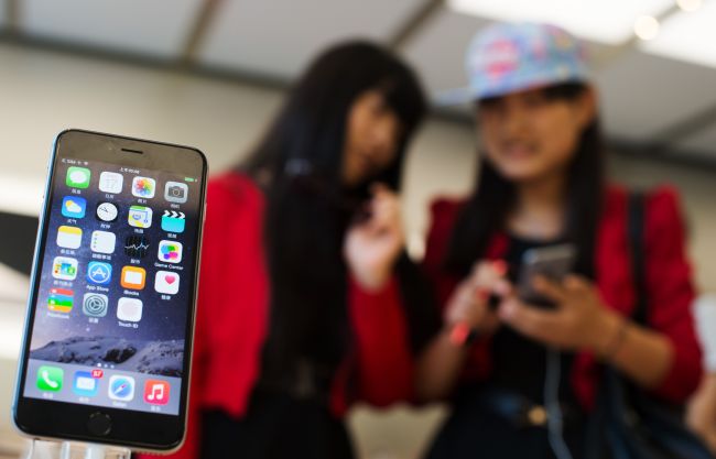 Customers check out the iPhone 6 in an Apple store in Shanghai.   AFP-Yonhap