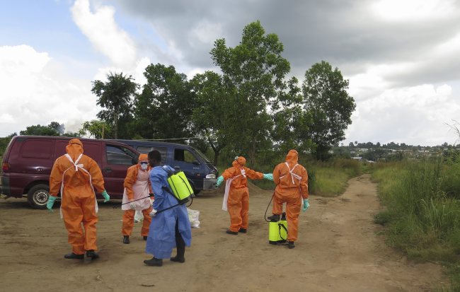 A Sierra Leone Red Cross burial team at Jobo Farm in Waterloo outside Freetown disinfects after recovering the bodies of a grandmother and her granddaughter believed to have died of Ebola and abandoned for four days in Sierra Leone on Monday.   EPA-Yonhap