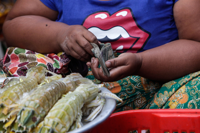 A vendor counts Burmese kyat banknotes at a market stall in Yangon, Myanmar, Oct. 14.    Bloomberg