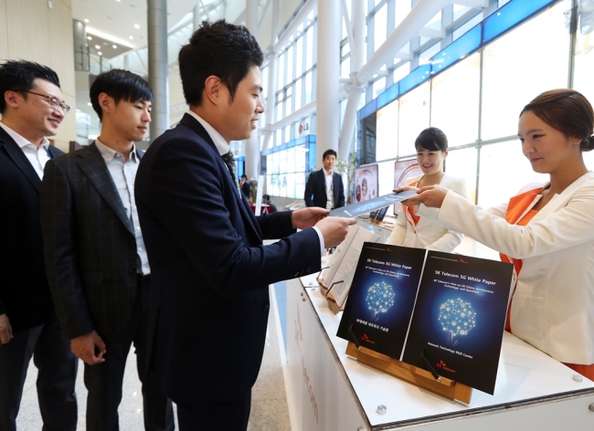 SK Telecom employees introduce a white paper on 5G technology at the firm’s booth at the 5G Global Summit, a sideline event of the ITU Plenipotentiary Conference in Busan, Tuesday.   SK Telecom