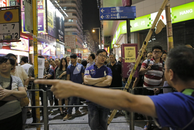 A pro-democracy protester (front) argues with a local resident (center) on a main road in the occupied area of the Mong Kok district in Hong Kong on Saturday.   AP-Yonhap