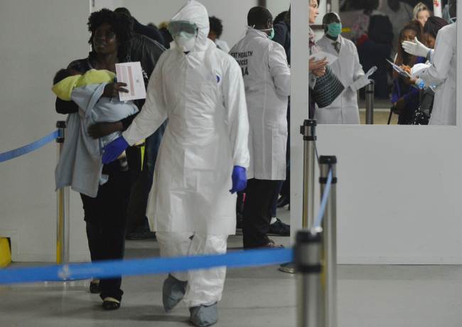 A woman carrying her child is led to an observation area by a health official at the Jomo Kenyatta International Airport in Nairobi on Tuesday.   AFP-Yonhap
