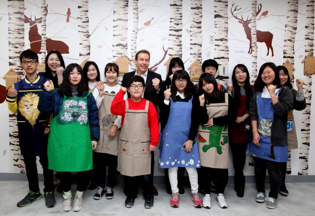 Han Sung Motor CEO Ulf Ausprung and Dream Gream students pose at a refurbished shelter for merchants at Seoul Jungang Market on Saturday.    Han Sung Motor