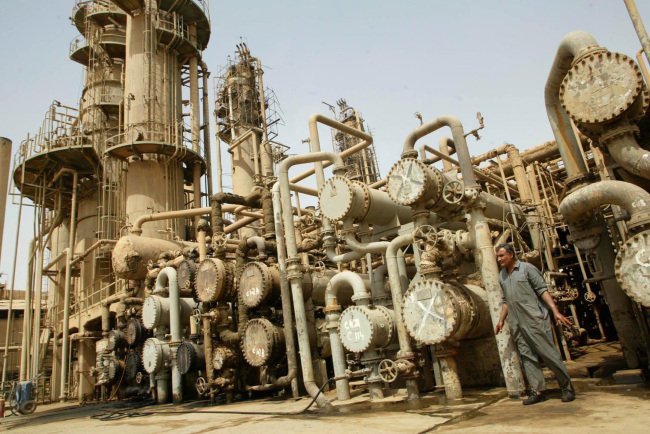 A worker walks past machinery at the al-Doura oil refinery in Baghdad, Iraq.    Bloomberg