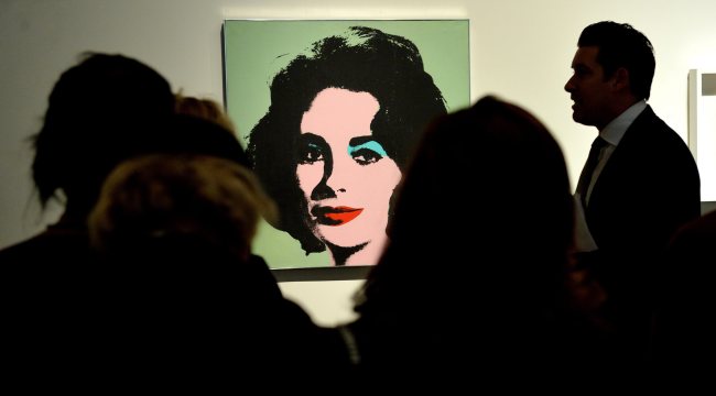 People look at the 1963 portrait “Liz #3 (Early Colored Liz)” by U.S. artist Andy Warhol during a preview of a contemporary art auction at Sotheby’s in New York on Oct. 31. The work, which will be up for auction on Nov. 11, is expected to sell for $30 million.   EPA-Yonhap