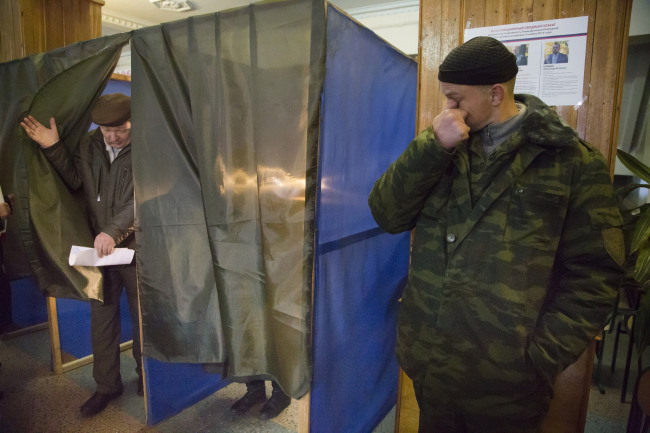 A pro-Russian rebel stands guard as a man leaves a voting cabin at a polling station during supreme council and presidential elections in the city of Donetsk, eastern Ukraine, Sunday.   AP-Yonhap