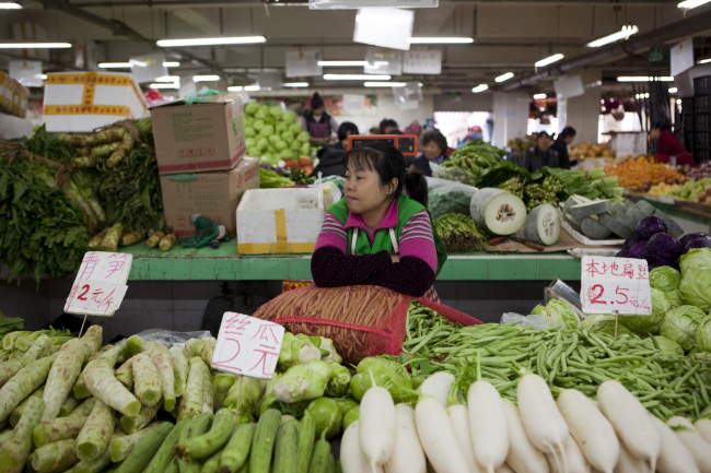 A vendor waits for customers at a market stall in Beijing.   Bloomberg