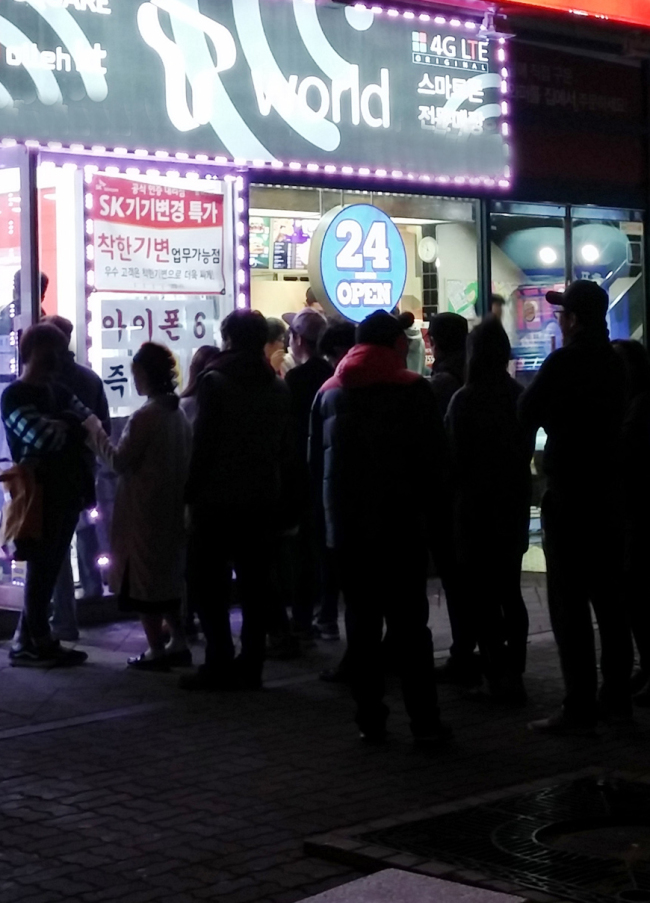 People line up in front of a telecom retail store to purchase Apple’s iPhone 6 at dawn in Goyang, Gyeonggi Province, Sunday. Telecom companies have been warned by regulators for providing excessive subsidies for the new smartphone.   Yonhap