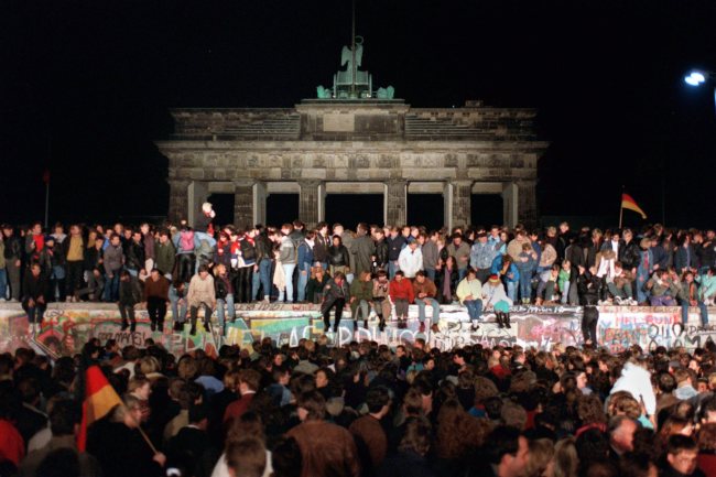 People celebrate the opening of the border between East and West Germany on the Berlin Wall in front of the Brandenburg Gate in Berlin on Nov. 10, 1989. (EPA-Yonhap)