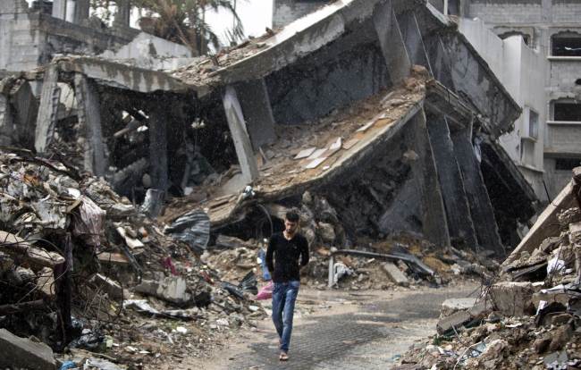 A Palestinian man walks in the rain next to the rubble of buildings destroyed during the 50 days of conflict between Israel and Hamas last summer, in the Shejaiya neighborhood of Gaza City on Monday.   AFP-Yonhap