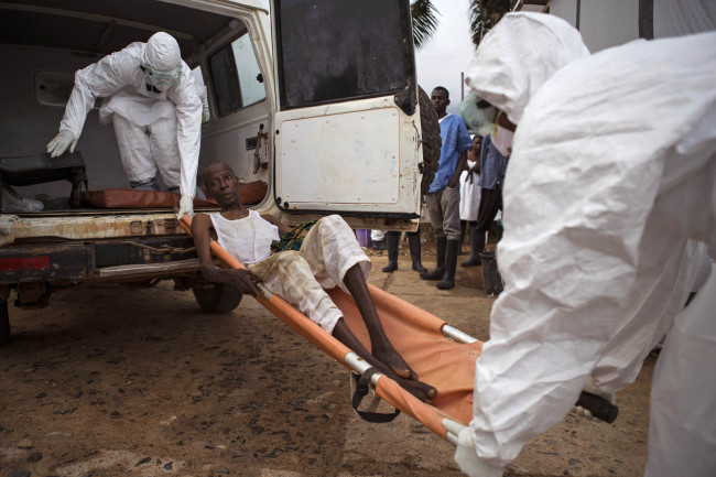 Health care workers load a man onto a ambulance as he is suspected of suffering from the Ebola virus in Kenema, Sierra Leone.   AP-Yonhap