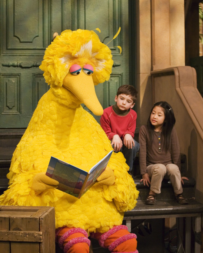Muppet character Big Bird reads to Connor Scott and Tiffany Jiao during a taping of the children’s program “Sesame Street” in New York on April 10, 2008.   AP-Yonhap