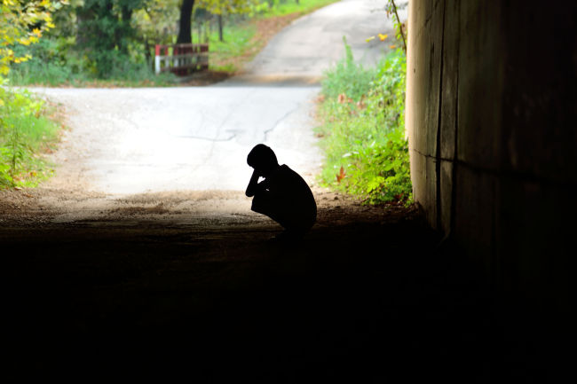An underprivileged child squats at the entrance of a tunnel.(123RF)