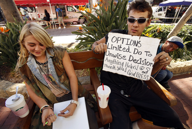 Daniella Hearn (left), 18, who grew up in Santa Barbara, California, with friend Frank “Wolv” Hunt, 20, from Georgia, use signs written on cardboard to lure change from pedestrians in Santa Barbara on Sept. 23. (Los Angeles Times/MCT)