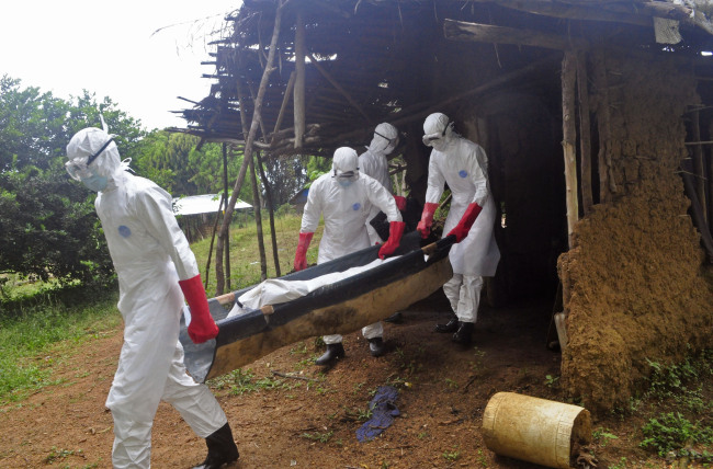 Health care workers carry the body of a middle-aged man who they suspected of dying from Ebola on the outskirts of Monrovia on Saturday.   AP-Yonhap