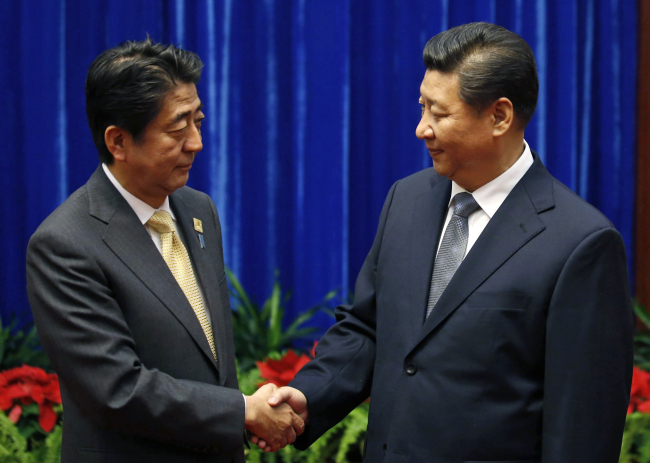 Japanese Prime Minister Shinzo Abe (left) and Chinese President Xi Jinping shake hands during their meeting at the Great Hall of the People, on the sidelines of the Asia Pacific Economic Cooperation meetings in Beijing on Monday.    AP-Yonhap