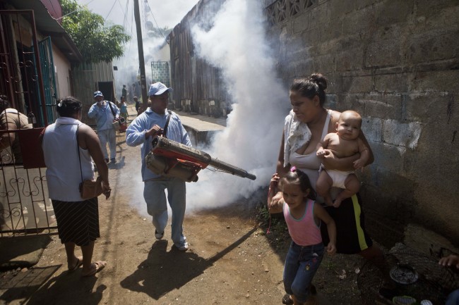 A woman with her children moves out of the way as a Health Ministry worker fumigates against mosquitoes that transmit dengue fever in Managua, Nicaragua. AP-Yonhap