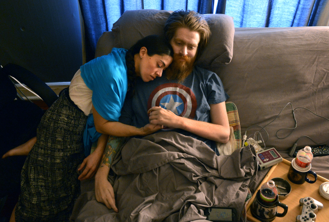 In this March 2013 file photo, Tomas Young, a paralyzed Iraq vet who became an outspoken critic against the war and subject of the documentary “Body of War,” sits with his wife and caregiver, Claudia Cuellar, in Kansas City, Missouri. (AP-Yonhap)