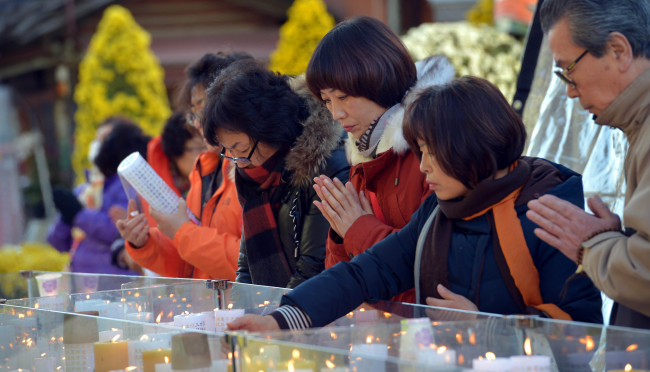 Families of the students who take the college entrance exam pray at Jogyesa Temple in Jongno, Seoul, Thursday. About 640,000 students took the exam at 1,216 schools nationwide.   Kim Myung-sub/The Korea Herald