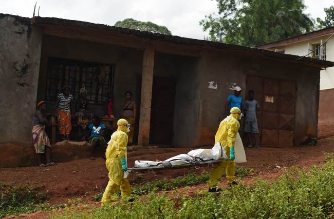 Health workers from Sierra Leone’s Red Cross Society burial team carry a body that they suspect of dying from Ebola in Freetown on Wednesday.   AFP-Yonhap