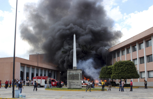 <YONHAP PHOTO-0580> Firefighters arrive to try to extinguish several burning vehicles in front of the state congress building after protesting teachers torched them in the state capital city of Chilpancingo, Mexico, Wednesday Nov. 12, 2014. Violent protests over the disappearance of 43 college students continue and are now threatening tourism in the nearby resort city of Acapulco ahead of a major holiday weekend when Mexicans traditionally flock to the beach, business leaders said Wednesday. Investigators say the 43 students from a rural teachers college were rounded up by local police, turned over to a drug gang and apparently killed, their corpses charred into ash and dumped into a river. (AP Photo/Alejandrino Gonzalez)/2014-11-13 08:42:15/ <저작권자 ⓒ 1980-2014 ㈜연합뉴스. 무단 전재 재배포 금지.>
Firefighters arrive to try to extinguish several burning vehicles in front of the state congress building after protesting teachers torched them in the state capital city of Chilpancingo, Mexico, Wednesday.   AP-Yonhap