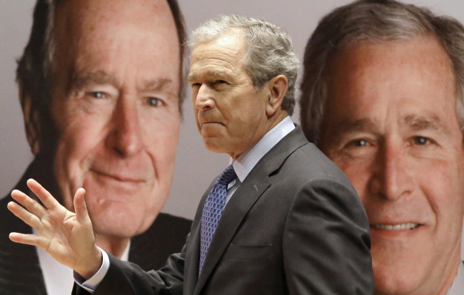 Former President George W. Bush passes by a portrait of himself and his father former President George H.W. Bush as he takes the stage to discuss his new book, “41: A Portrait of My Father” at his father’s presidential library in College Station, Texas, Tuesday. (AP-Yonhap)